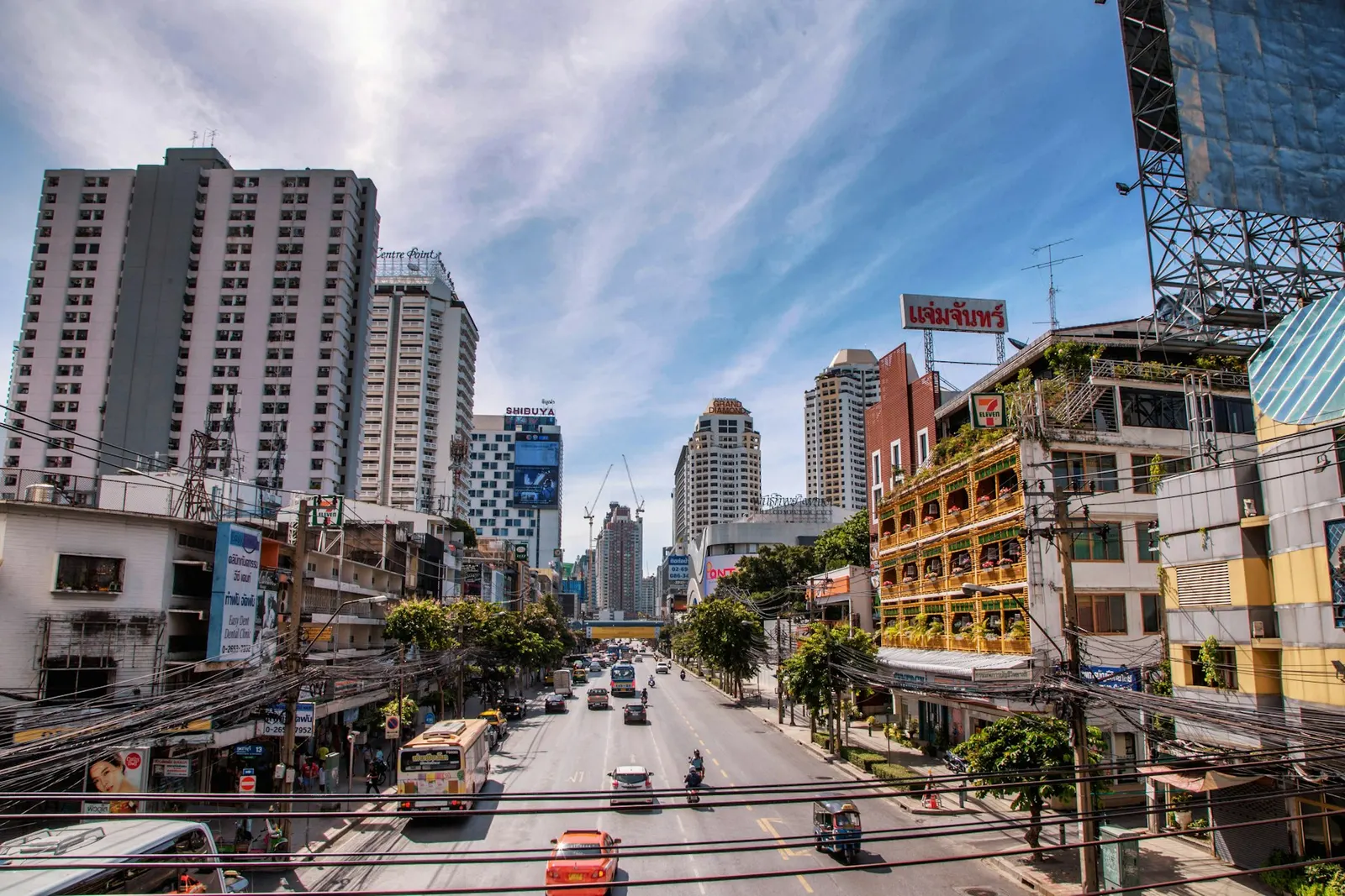 A busy Bangkok street lined with apartments, shops and overhead cables